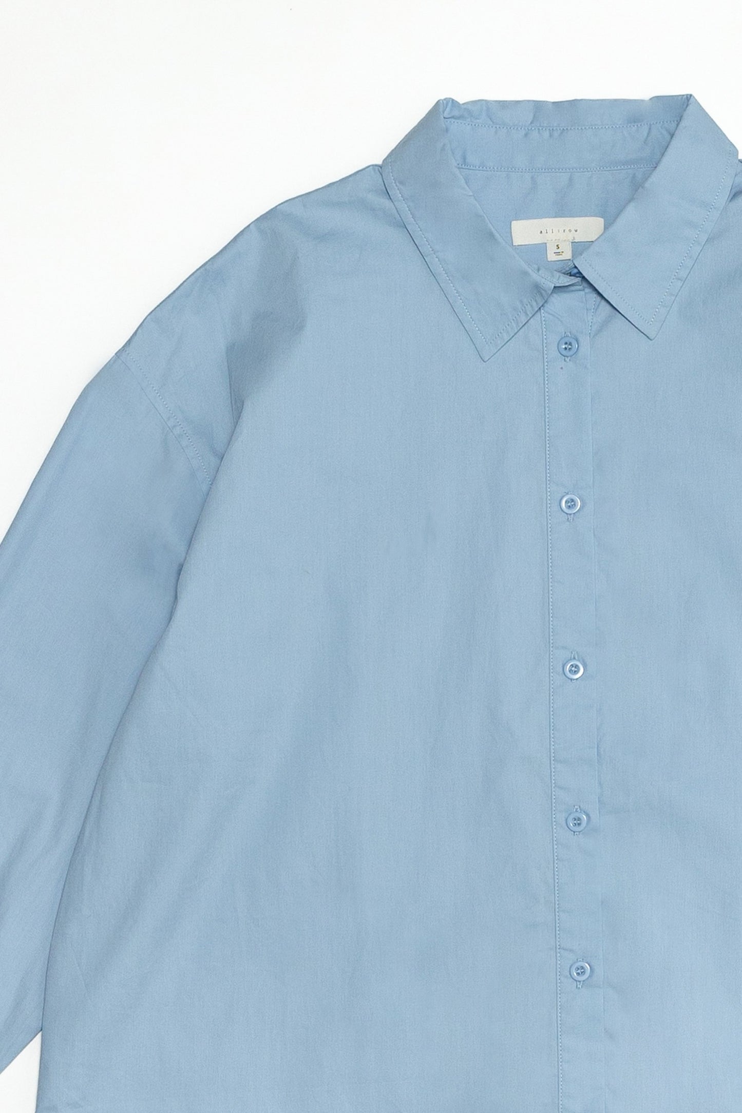 Up close of the blue button down shirt and showing how classic it looks and 100% made from cotton. 